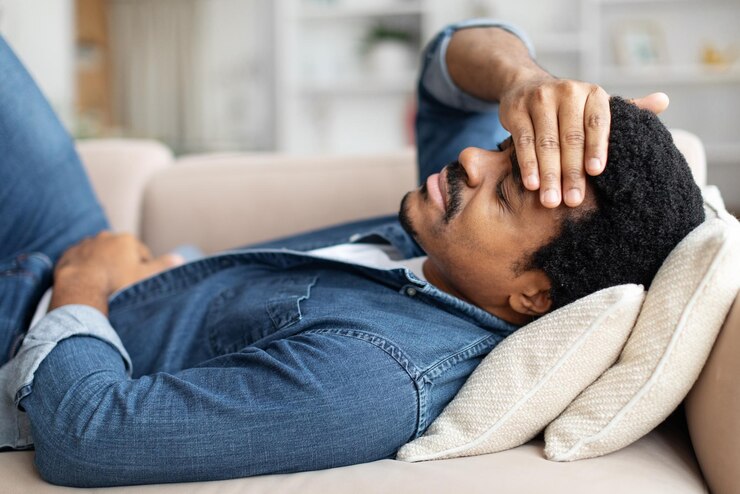 Photo un homme noir se sent mal à la maison, souffre de maux d'estomac et de maux de tête.