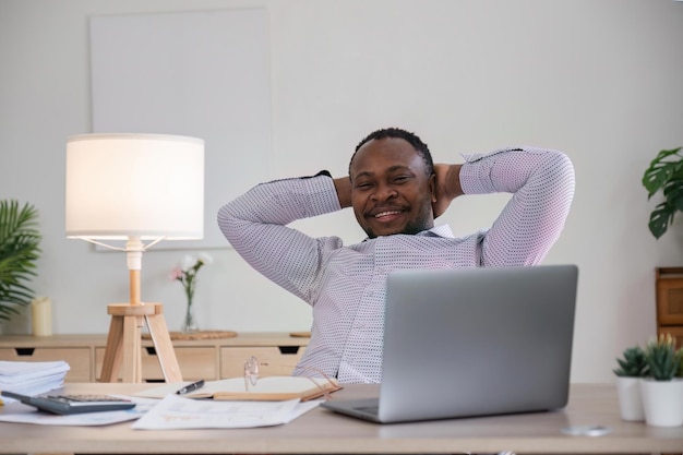 Homme noir souriant à l'aide d'un ordinateur portable à la maison dans le salon Heureux homme d'affaires mature envoyer un e-mail et travailler à la maison