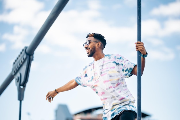 Homme noir souriant à lunettes de soleil appréciant heureux avec le bras tendu profitant du moment