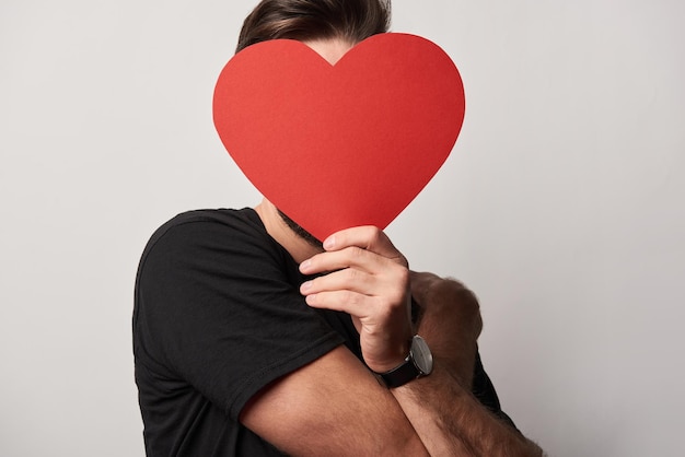 Homme en noir avec visage obscur et carte coeur découpée en papier vide