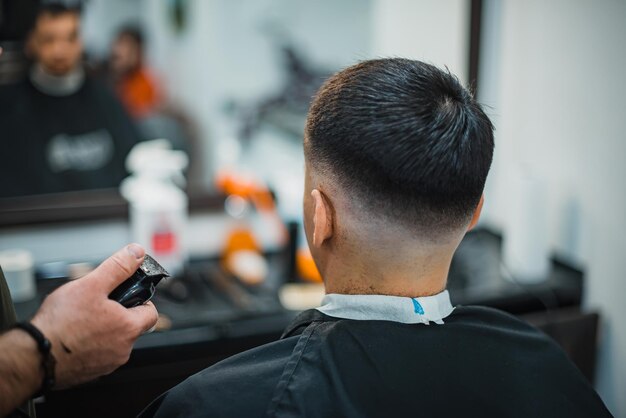 L'homme obtient une coupe de cheveux cool dans un salon de coiffure. Barber fabrique le rasoir électrique cut man. Chef de soins pour hommes. Mise au point douce.