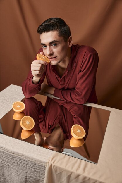 Homme avec des oranges sur le miroir sur le fond de tissu vue de dessus de table