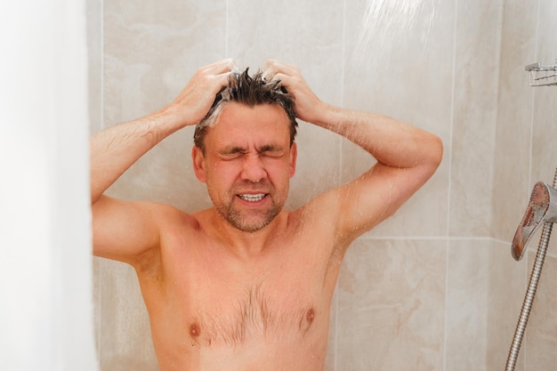 Photo un homme ordinaire se baigne dans la douche et se lave les cheveux avec du shampoing