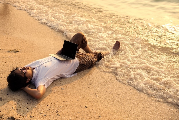 homme avec ordinateur sur la plage