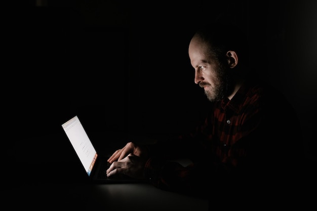 Homme avec ordinateur portable dans le noir