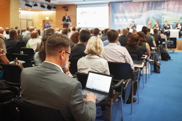 Homme avec ordinateur portable sur présentation d'une grande entreprise