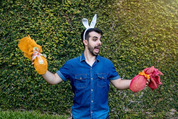 Homme avec des oreilles de lapin de pâques tenant des oeufs de pâques mur vert en arrière-plan