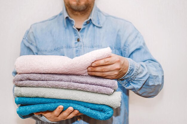 L'homme organise et nettoie la maison Une pile de serviettes éponge propres à la main