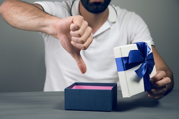 Un homme a ouvert un cadeau et montre un pouce vers le bas