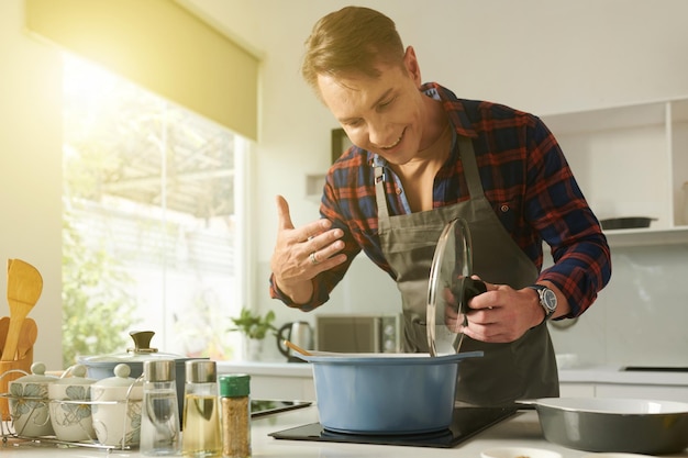 Homme ouvrant une casserole avec du bouillon