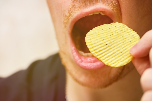 L'homme ouvre la bouche, y apportant des frites.