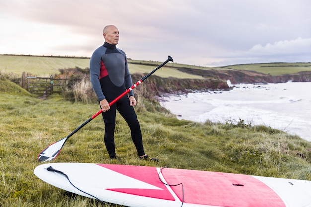 Homme avec paddle board au-dessus des falaises