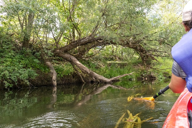 un homme pagaie dans une rivière avec un bâton à la main.