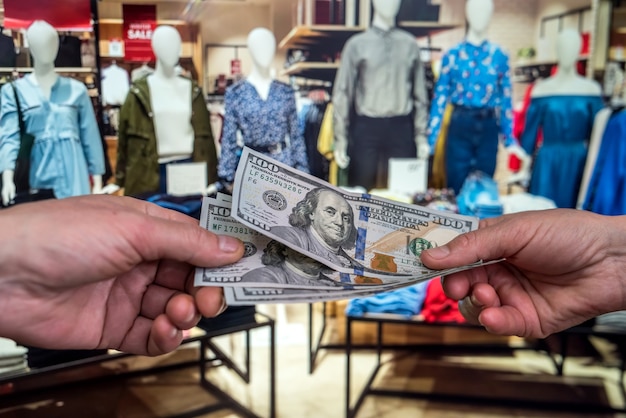 L'homme paie en dollars pour acheter des vêtements dans un magasin. concept de magasinage