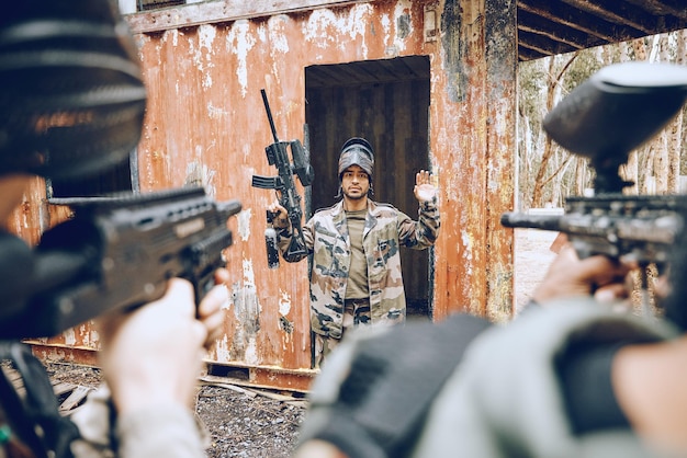 Un homme de paintball se rend avec un champ de bataille de soldats et d'armes à feu et de remise en forme avec une mission militaire et perd le jeu. Camouflage sportif et armée en plein air avec un joueur perdu pris et visant la cible avec la guerre