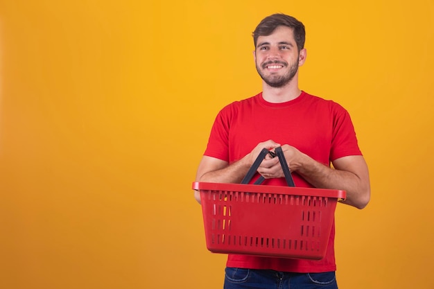 Homme avec panier de supermarché sur fond jaune