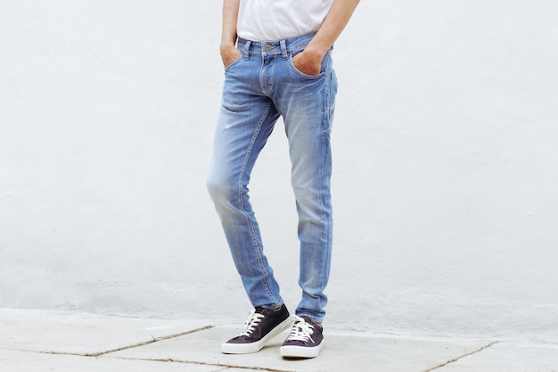 Homme avec un pantalon en denim bleu et des baskets debout