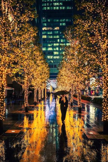 Un homme avec un parapluie dans une ruelle éclairée par une nuit de pluie à Tokyo, au Japon