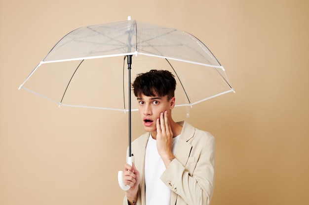 Un homme avec un parapluie ouvert dans une veste de protection contre la pluie fond beige