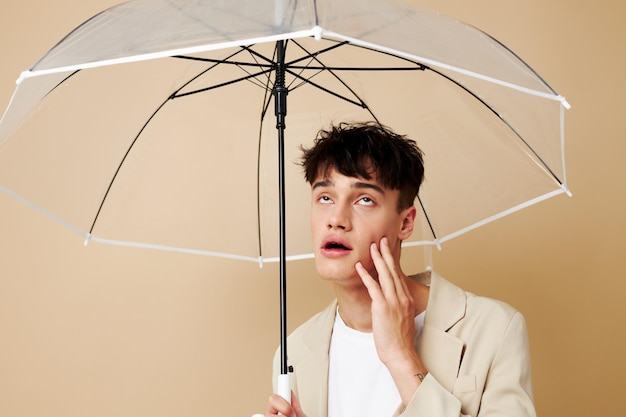 Un homme avec un parapluie ouvert dans une veste de protection contre la pluie fond beige