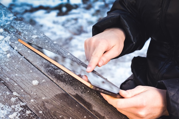 Un homme parcourt des photos sur une tablette alors qu'il est assis à une table en bois