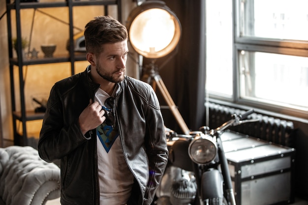 Homme parfait. Jeune hipster en blouson de cuir debout dans la chambre.