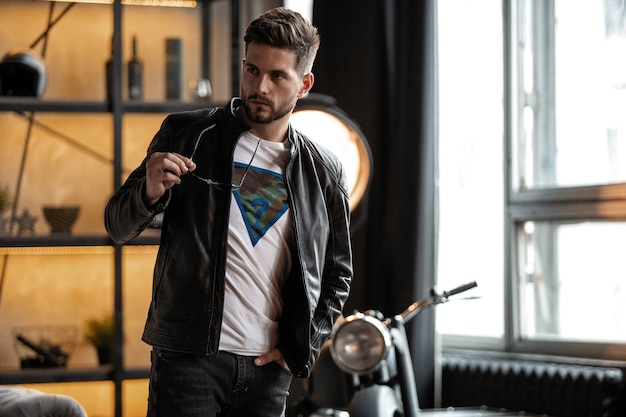 Homme parfait. Jeune hipster en blouson de cuir debout dans la chambre.