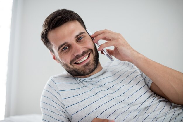 Homme parlant au téléphone mobile dans la chambre à la maison