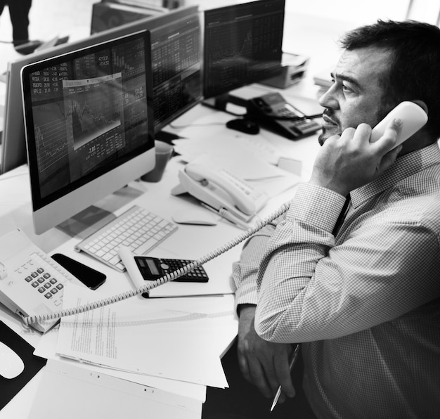 Homme parlant au téléphone en regardant l'analyse du marché boursier sur l'écran de l'ordinateur