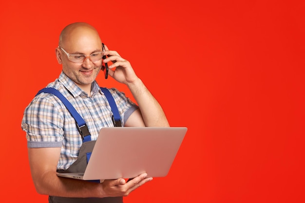 L'homme parle au téléphone et regarde un ordinateur portable qu'il tient dans ses mains