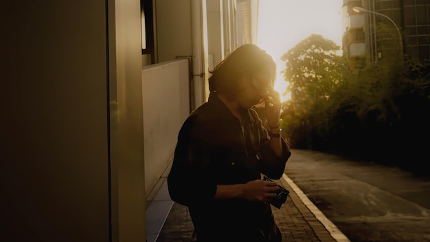 Photo un homme parle sur un téléphone portable devant un coucher de soleil.