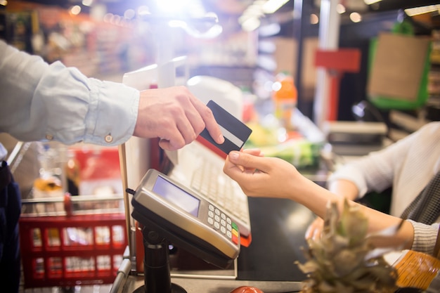 Homme payant avec carte de crédit en supermarché