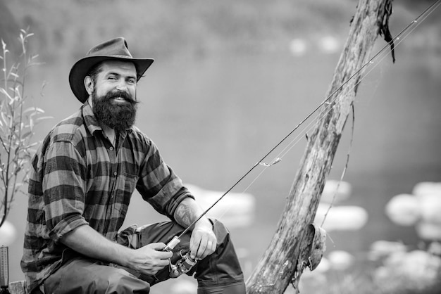 Homme pêchant assis seul pendant le processus de pêche près du lac passe-temps et activité sportive fisherma