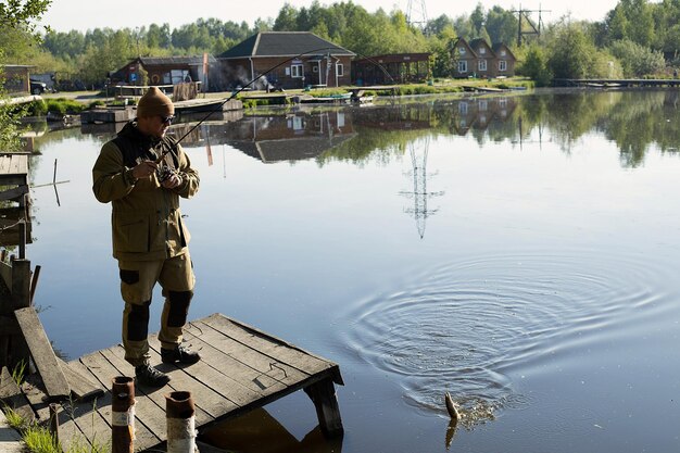 Homme pêchant sur une jetée en bois près du lac