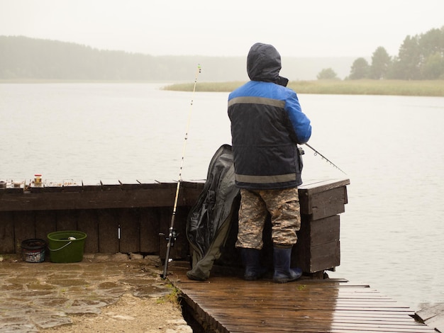 Homme pêchant sur la jetée un jour pluvieux et brumeux