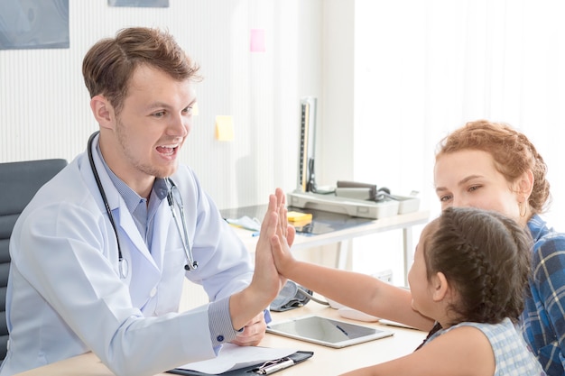 Photo homme pédiatre donnant une bosse de poing (high five to), rassurant et discutant d'un enfant lors d'une opération.