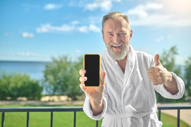 Homme En Peignoir Montrant Son Smartphone Sur Le Balcon