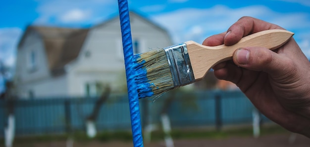 Un homme peint un cadre en fer avec de la peinture jaune et bleue