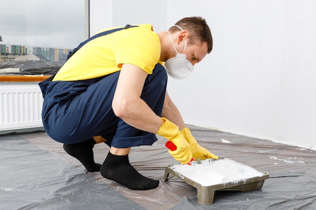 L'homme peint les murs et le plafond en blanc Peinture et réparation de la pièce.