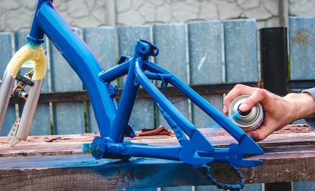 Un homme peint un vélo avec de la peinture en aérosol