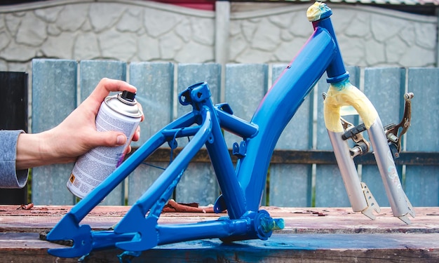 Un homme peint un vélo avec de la peinture en aérosol