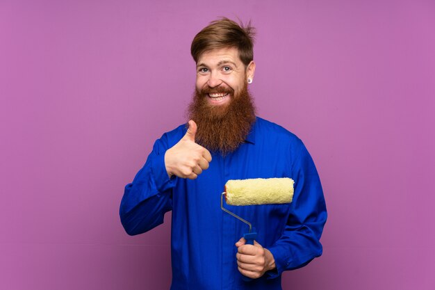 Homme Peintre Avec Une Longue Barbe Sur Un Mur Violet Isolé Donnant Un Geste Du Pouce Levé