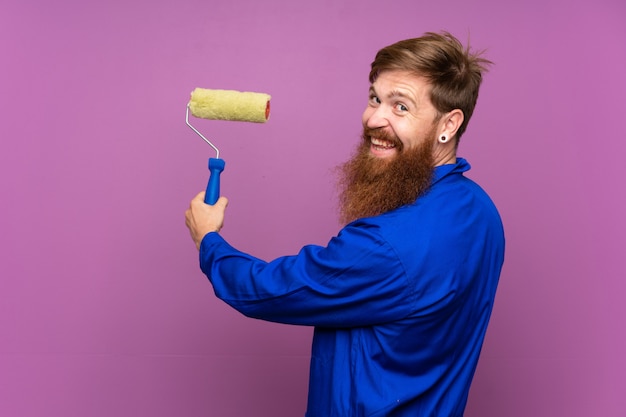 Homme peintre avec une longue barbe sur un mur violet isolé