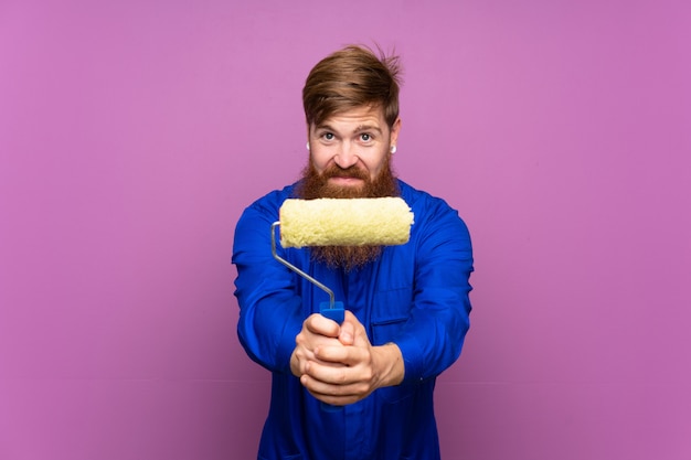 Homme peintre avec une longue barbe sur un mur violet isolé