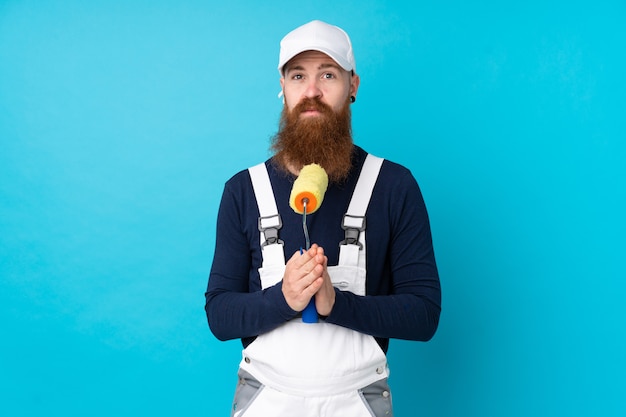 Homme peintre avec longue barbe sur plaidoirie bleu isolé