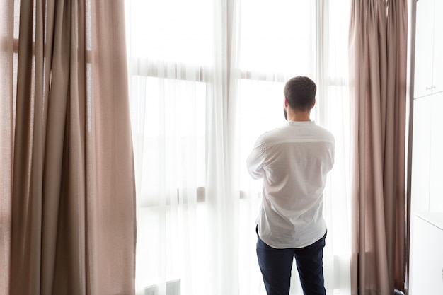 Homme pensif debout près de la fenêtre