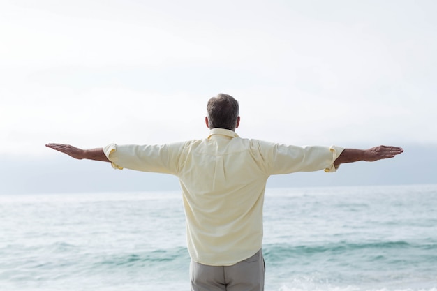 Homme pensif debout près de la mer, bras tendus