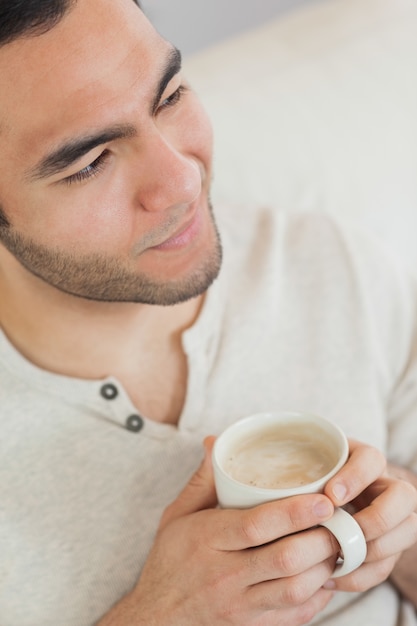 Homme pensif souriant tenant une tasse de café