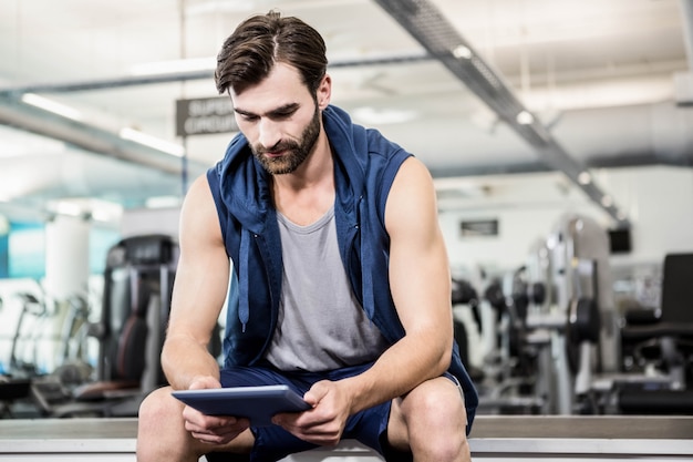 Homme pensif avec tablette au gymnase