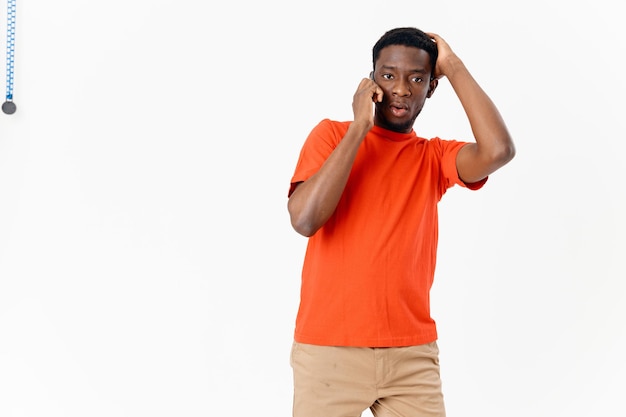 Homme perplexe d'apparence africaine parlant au téléphone sur fond clair et short Tshirt